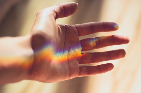 Hand wird beleuchtet, Regenbogenmuster reflektiert auf ihr