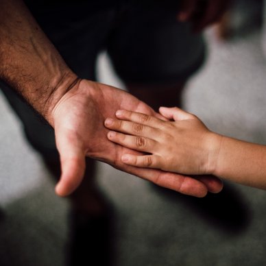 Kleine Hand liegt auf großer Hand 