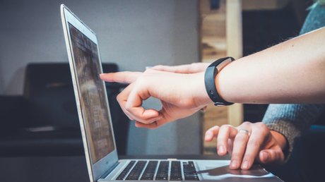 Ein Mitarbeiter zeigt einem anderen was am Laptop
