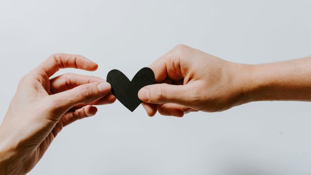 Hände, die sich ein Papierherz reichen