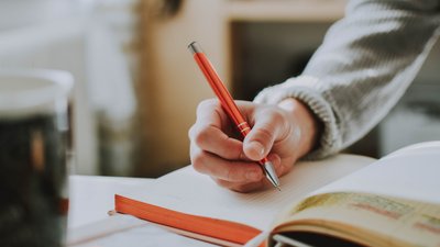 Person schreibt ins Notizbuch