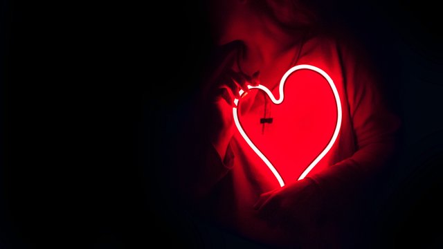 Frau hält ein neonglühendes Herz