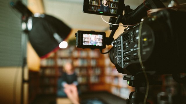 videokamera die eine person vor einem bücherregal filmt